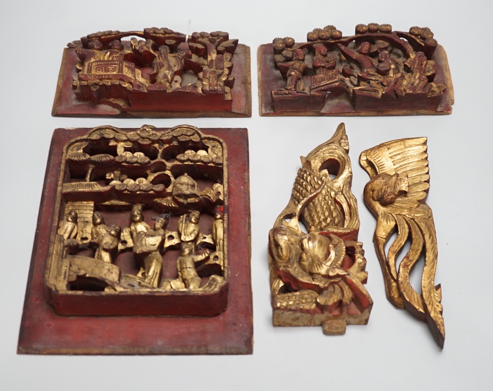 Three Chinese gilded and lacquered wood figural panels and two similar dragon and phoenix crest pieces (5), late 19th century